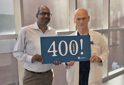 Dr. Sekela and Dr. Raj holding a sign that reads over 400 hearts