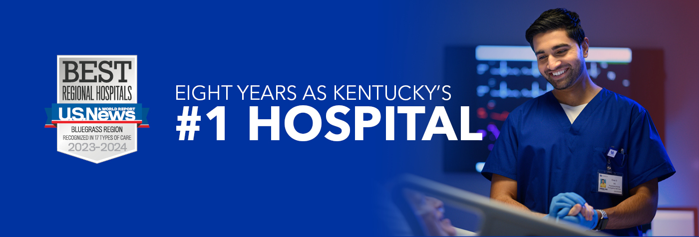 A smiling male provider wearing blue scrubs holds the hand of his patient, an older man in a hospital bed who is smiling and speaking. A headline on the image reads "Eight years as Kentucky's #1 hospital." Superimposed on the image is a badge that reads "US News & World Report Best Regional Hospitals, Bluegrass Region, Recognized in 17 Types of Care, 2023–2024."