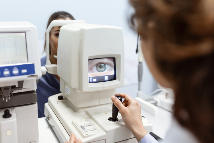 Doctor testing for eyes with special optical apparatus in modern clinic. Ophthalmologist examining eyes of a patient using digital microscope during a medical examination in the ophthalmologic office