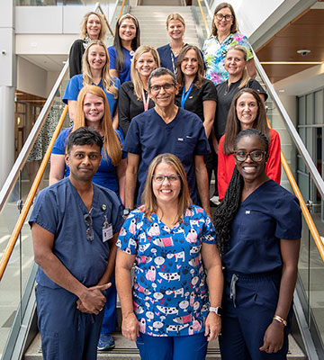 A group of smiling men and women stand together on a flight of stairs.