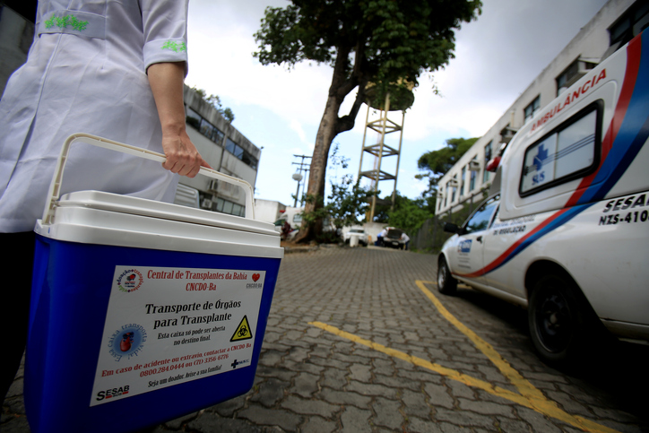 A person carries an organ from an ambulance in an appropriately marked container
