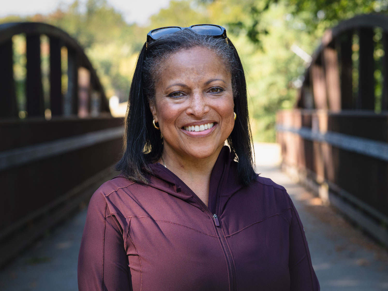 A close-up of Maria Braman, who's standing on a wooden bridge and smiling toward camera.