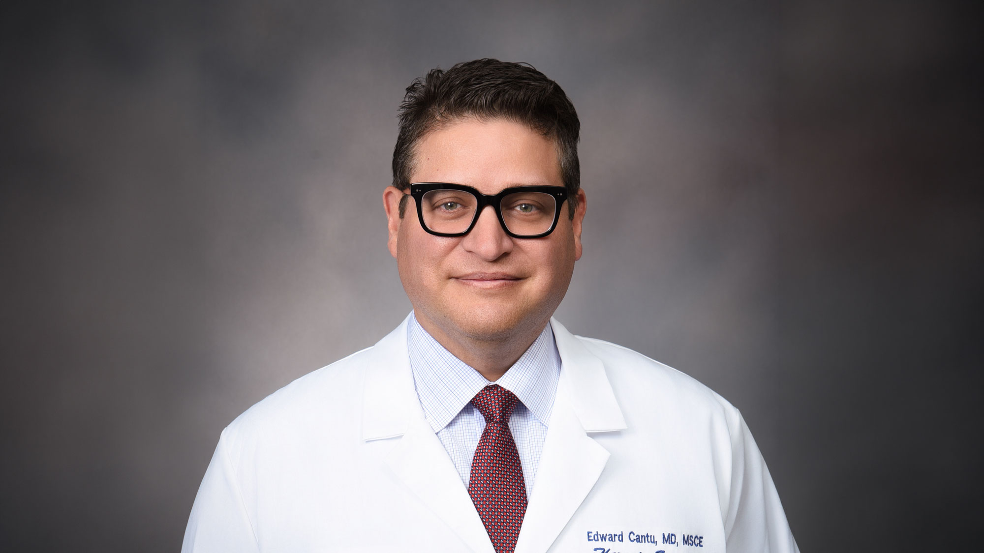 Dr. Edward Cantu against a gray background, he's wearing a white labcoat