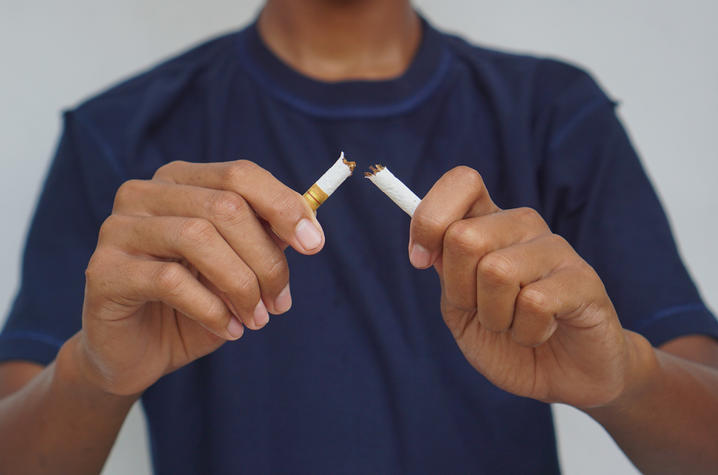man breaking a cigarette in half