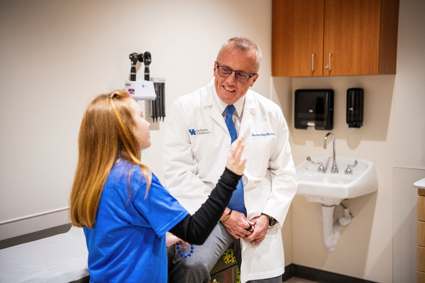 Dr. Scottie Day consulting with a young patient who's seated in an exam room