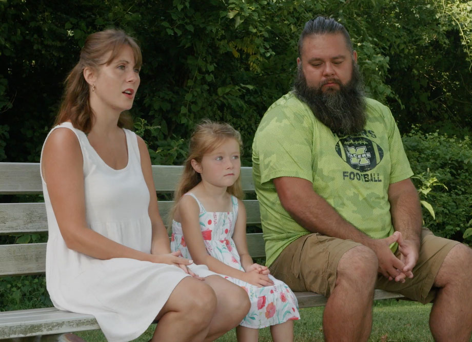 Jamie Newton, Izzy Newton and Joshua Newton sit on a park bench while looking off camera