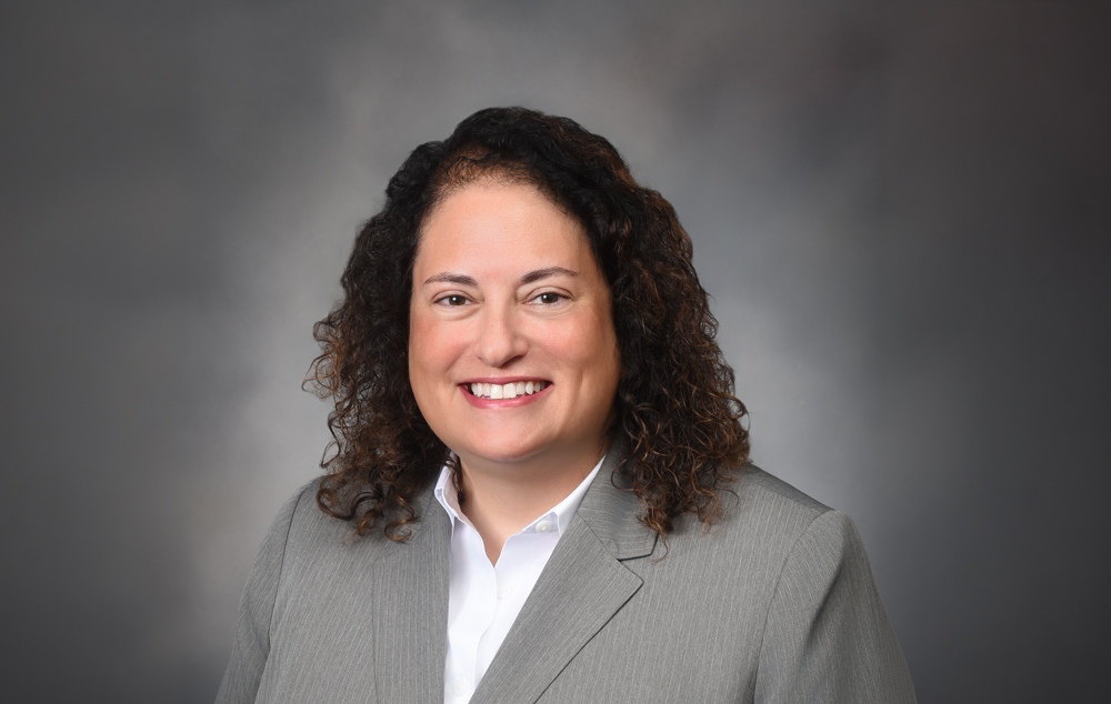 Dr. Julie Lang smiling toward camera while posed against a gray background