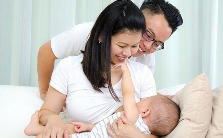 A father smiles as a mother breastfeeds.