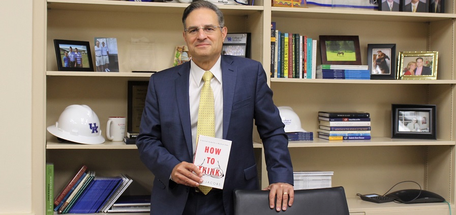 Dr. Robert DiPaola holds a book in his office.