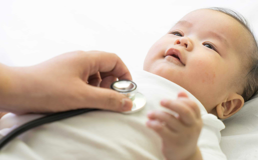 A doctor examines an infant using a stethoscope.