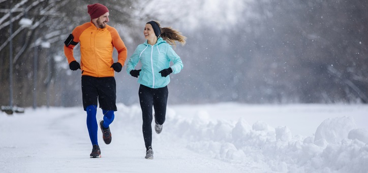 Couple run together in the snow.