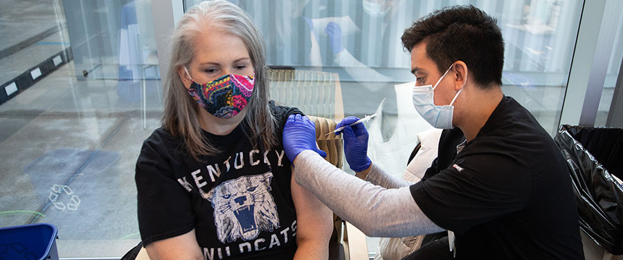 Woman wearing Kentucky Wildcats shirt receives vaccination