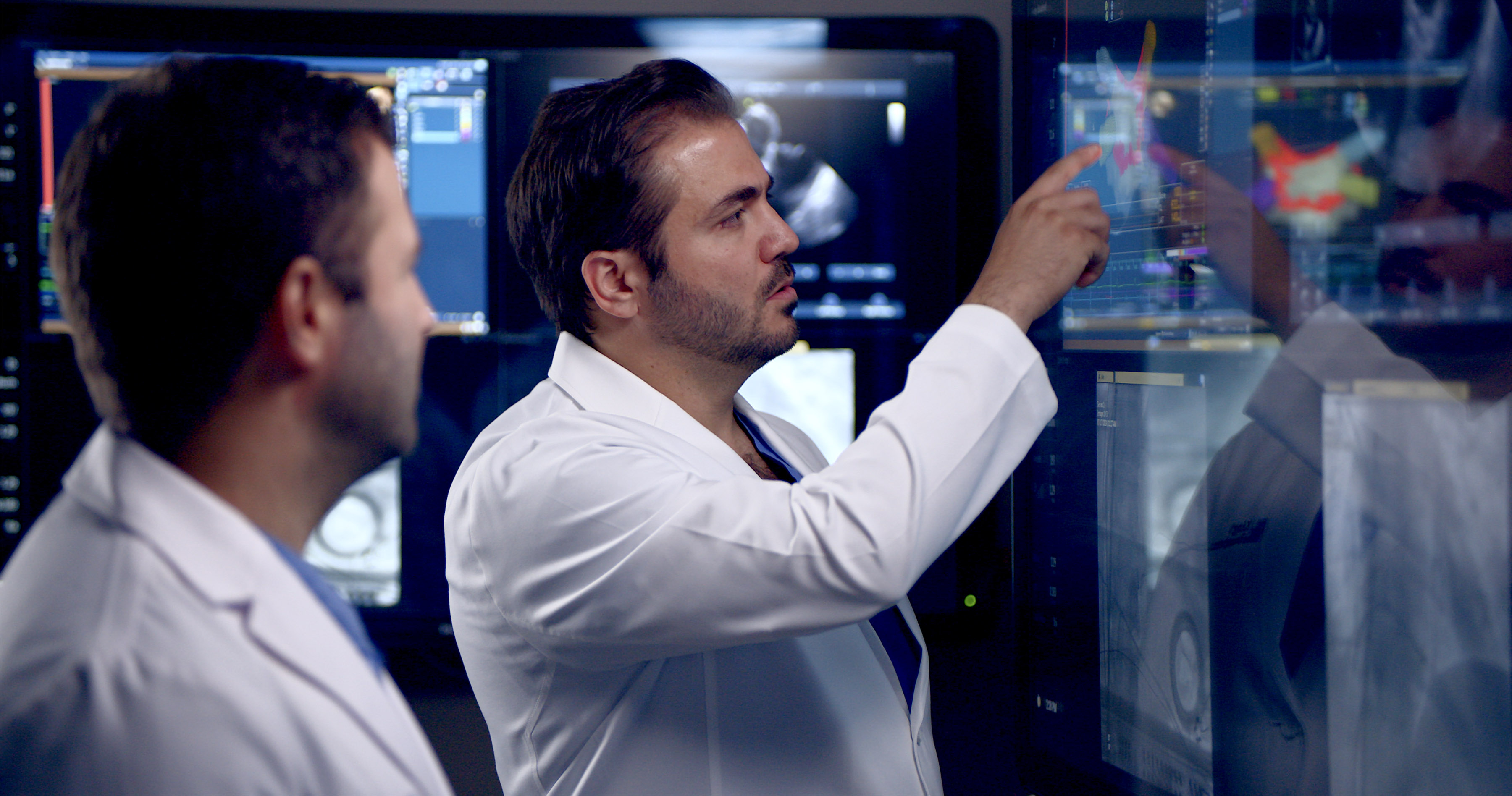 Two health care providers look at images on a screen.