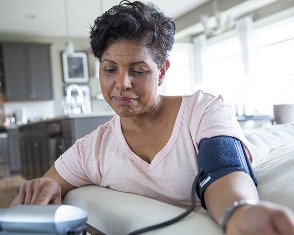 Adult Black woman checks her blood pressure at home