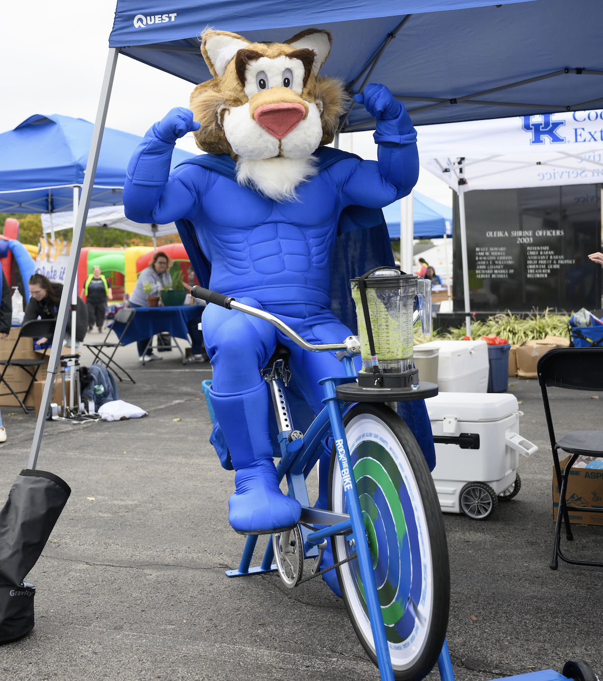 Wally Cat riding the smoothie bike at a festival. 