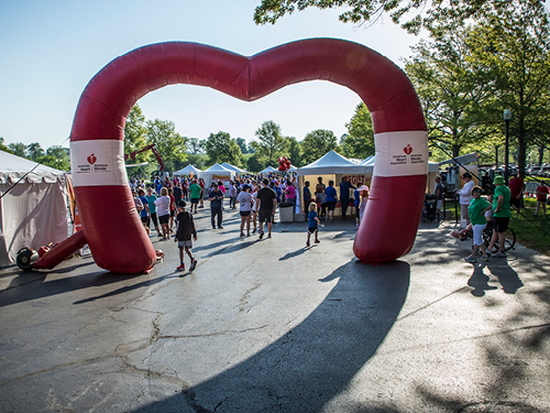 An inflatable arch in the shape of a heart seen at a community event.