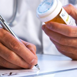 A doctor holding a pill bottle writes a prescription.