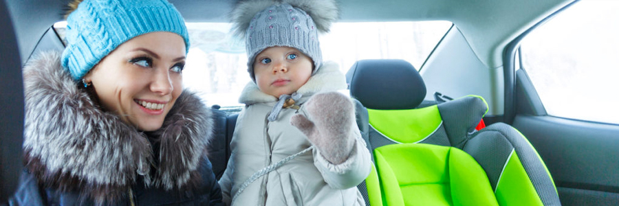 Mother and toddler daughter dressed in winter clothes inside a car.