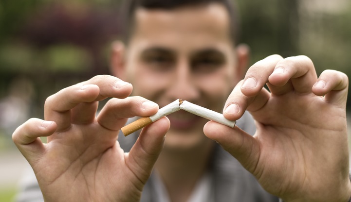 Young man breaks cigarette in half