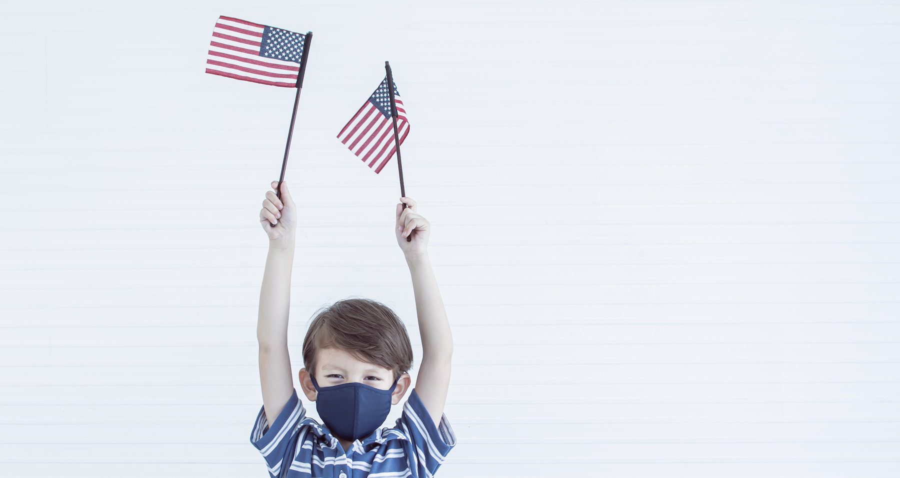 Boy wearing a mask and holding an American flag.