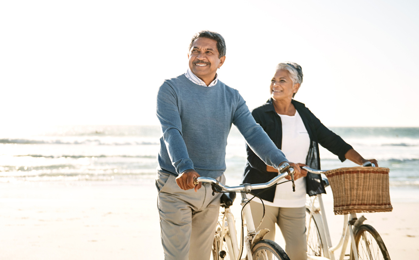 A senior couple with bicycles on the beach.