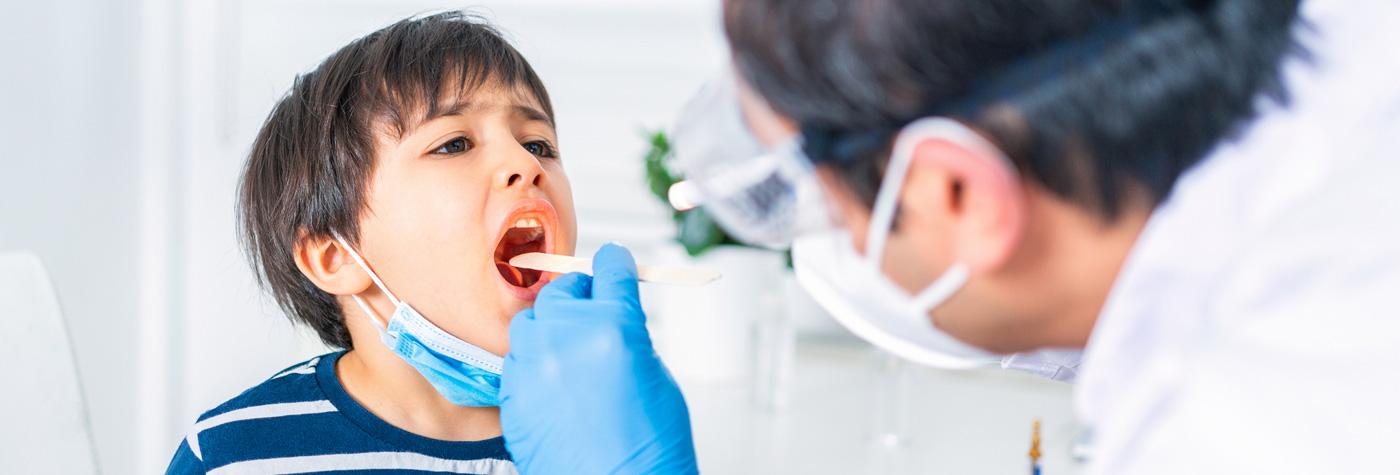 Doctor uses tongue depressor to examine a boy's throat