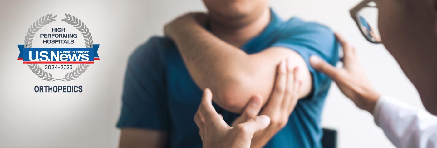 A doctor examines a patient's elbow. Superimposed on the image is a badge that reads US News & World Report High Performing Hospitals, Orthopedics, 2024-2025.