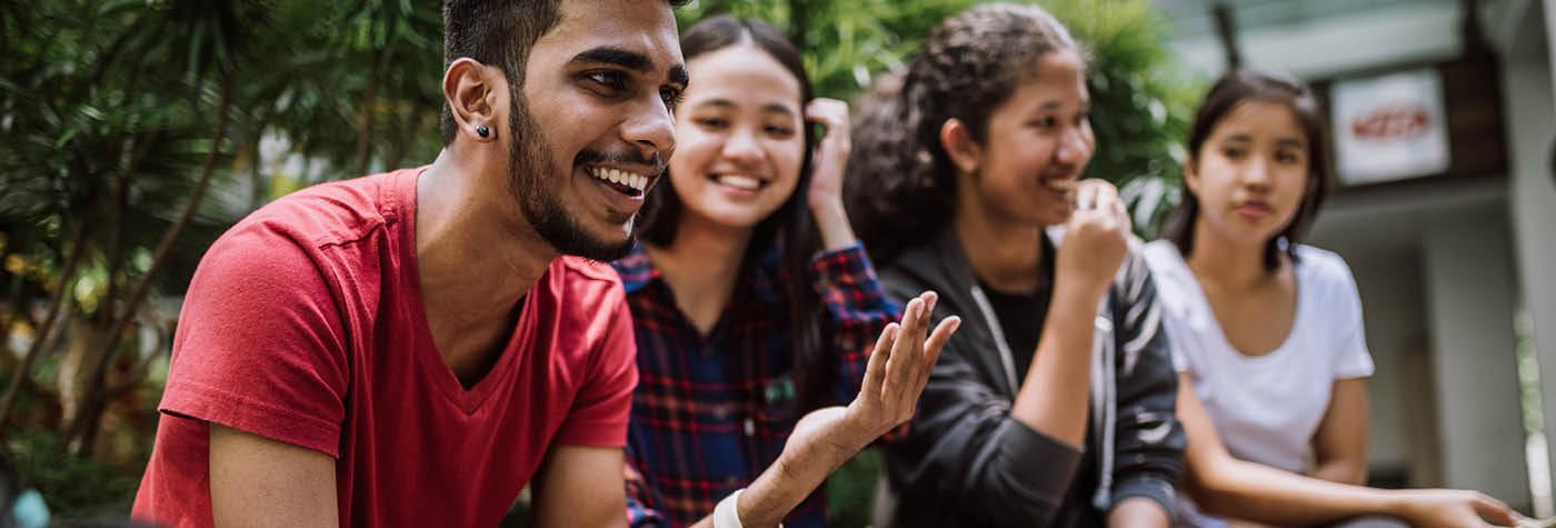 A group of young adults sit side by side smiling.