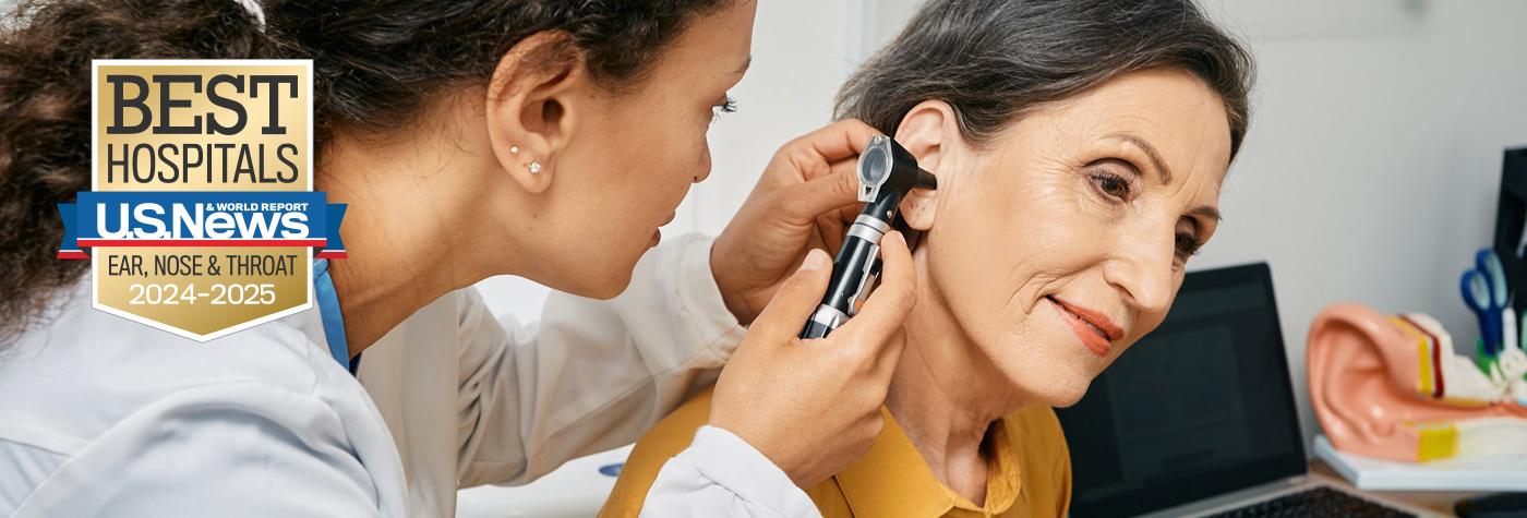 A provider uses an otoscope to look in a patient's ear. Superimposed on the image is a badge that reads U.S. News and World Report Best Hospitals - Ear, Nose & Throat - 2024–2025