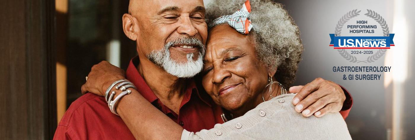 An older African-American man and woman embrace while facing the camera. A badge superimposed on the photo reads "US News & World Report 2024-2025 High Performing Hospitals, Gastroenterology & GI Surgery."