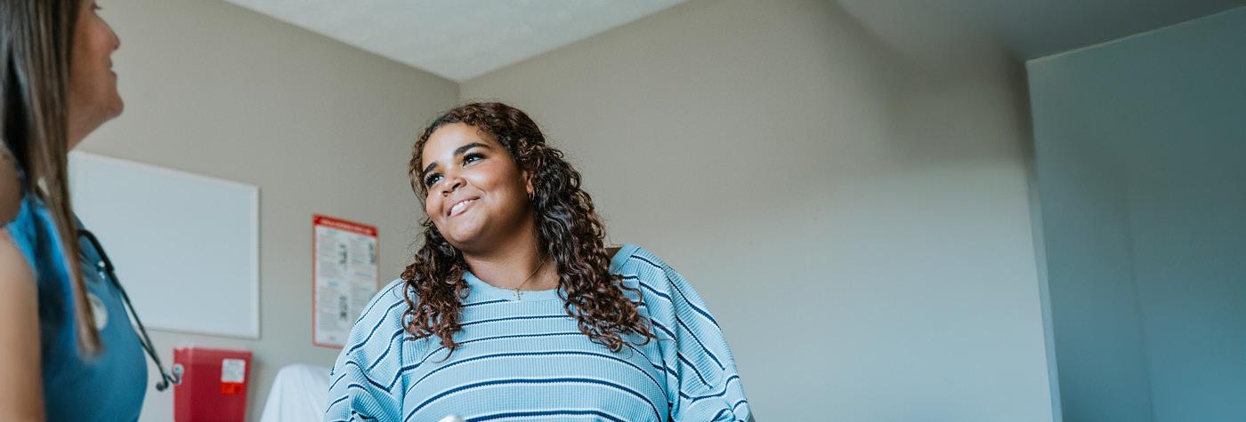 A young woman speaks with a woman wearing teal blue scrubs.