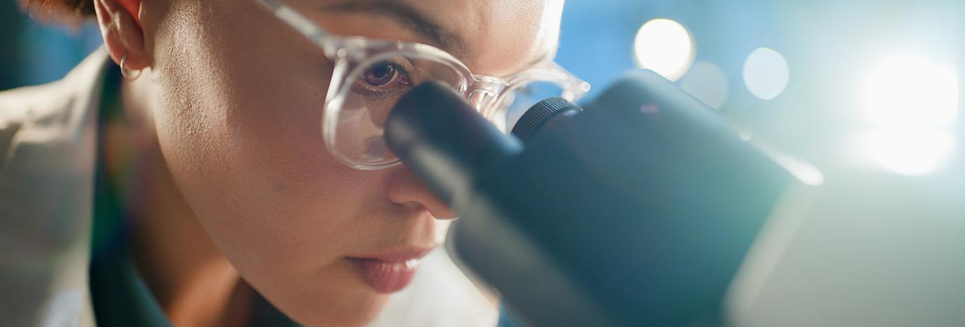 scientist looks into microscope