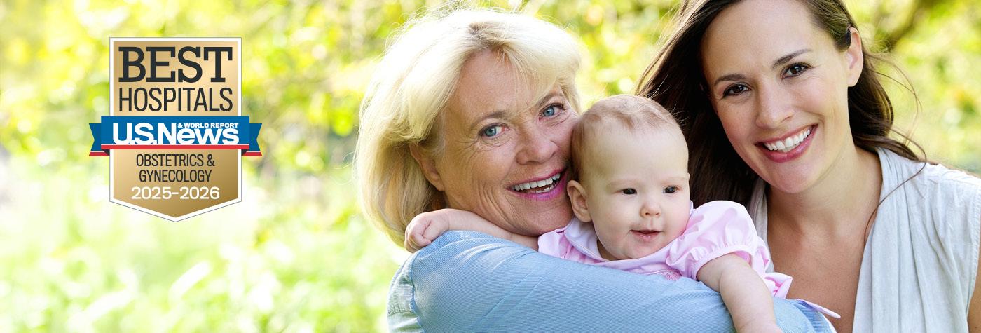 An older woman and a younger woman smile while the older woman holds a baby in a pink blouse. A badge on the image reads "US News & World Report Best Hospitals, Obstetrics & Gynecology, 2025-2026."