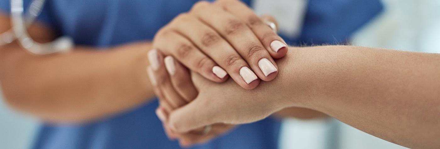two adults clasp hands to comfort one another