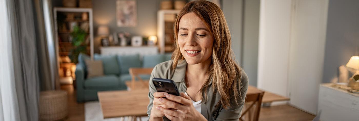 A woman smiles as she texts on her mobile phone