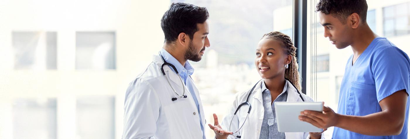 Three doctors have a conversation with one another.