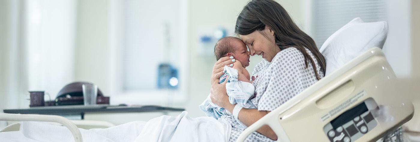 A woman in a hospital bed holds her newborn