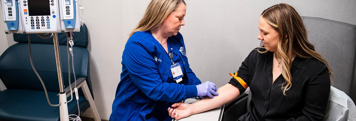 Technician inserting needle into patient's arm for an infusion