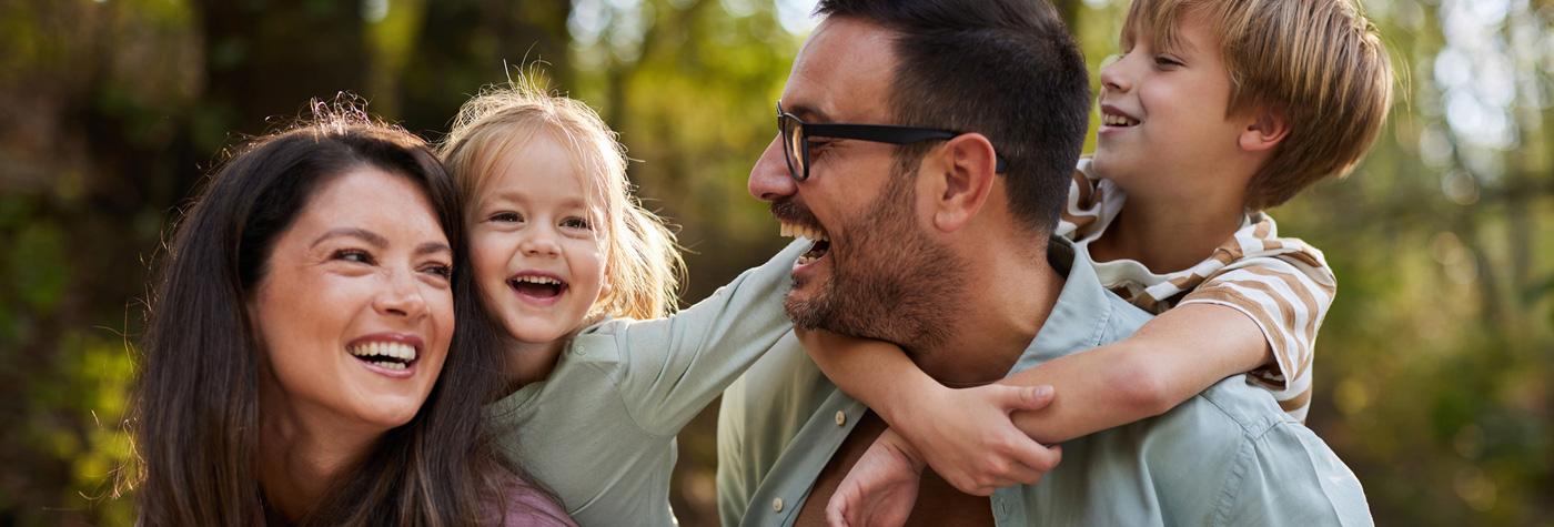 Husband and wife, with their two children hanging on their backs in playful time.