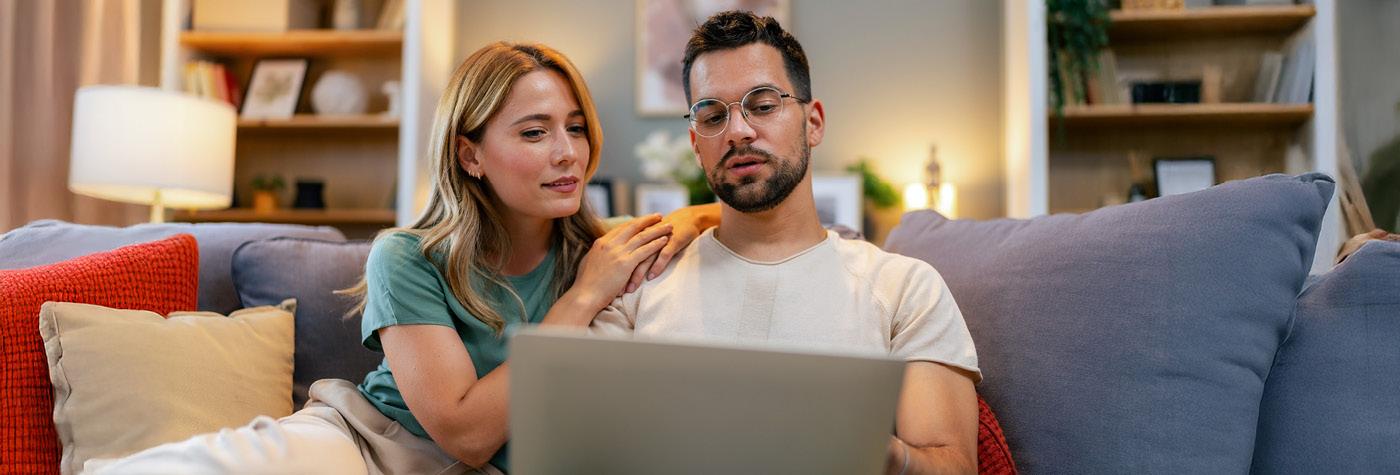 Couple sitting on a blue couch using a laptop