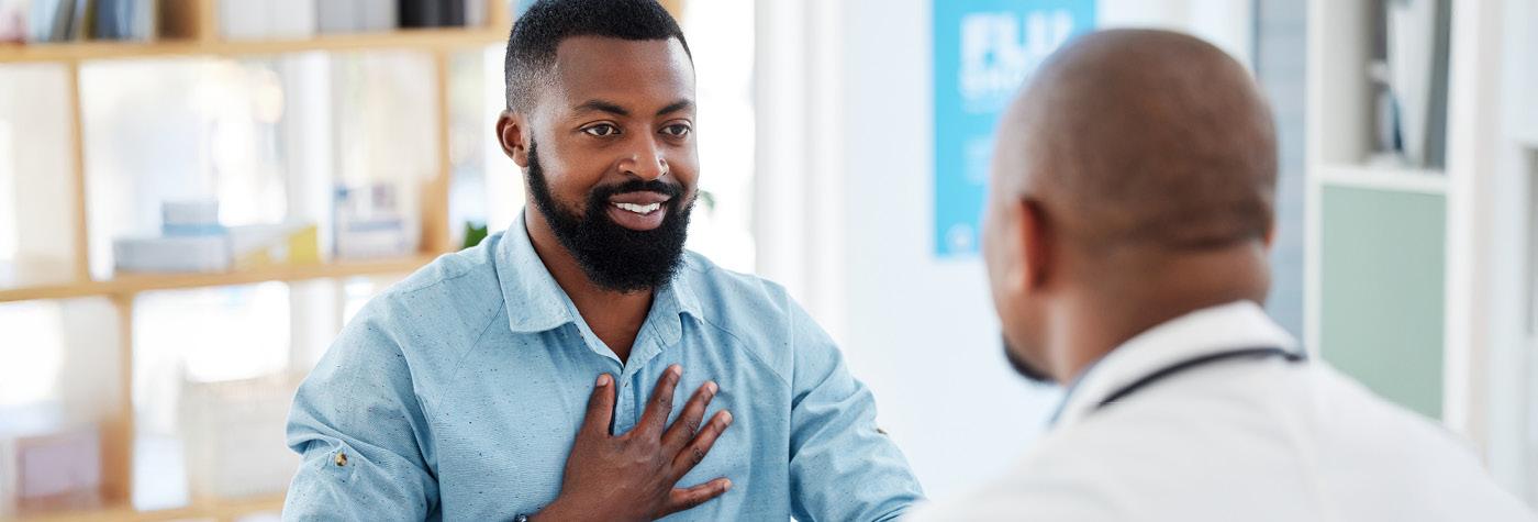 A man smiles as he speaks with his doctor, who we see over the shoulder of.