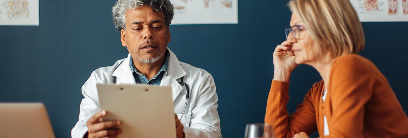 A doctor points out something on a clipboard to a female patient.
