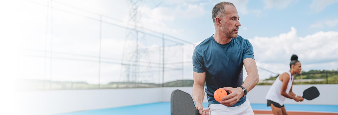 A man and woman play pickleball.