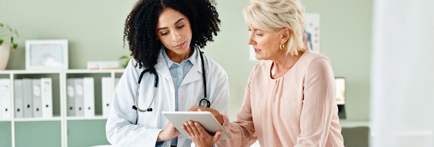 A patient and provider look at a tablet reviewing information.