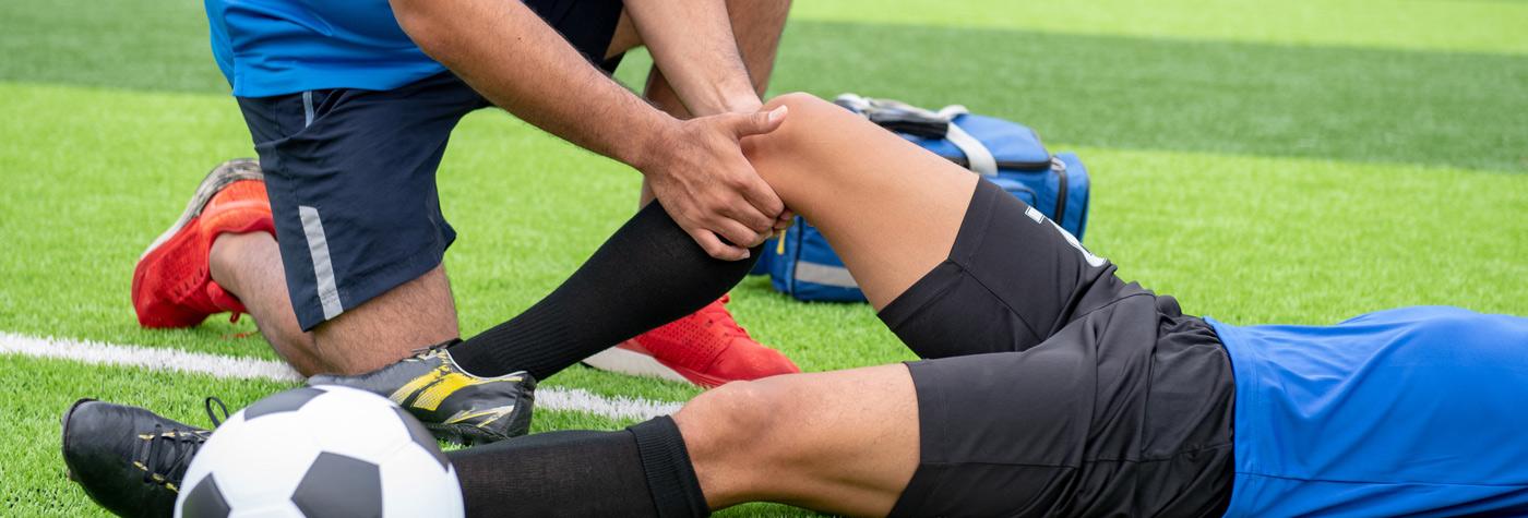 Trainer examines a soccer player's knee