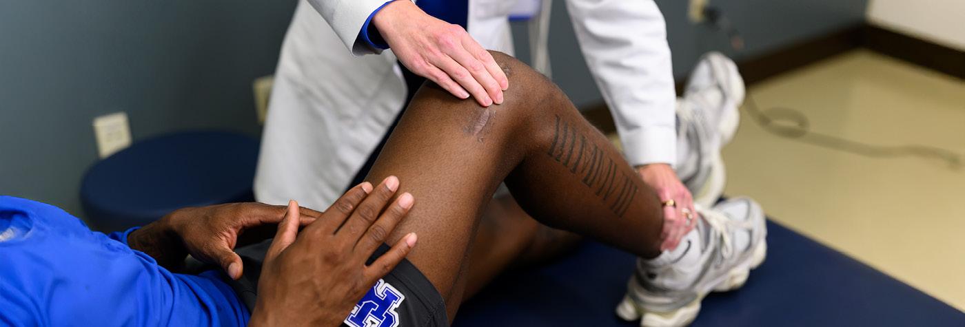 A UK sports medicine physician examines a UK athlete's knee