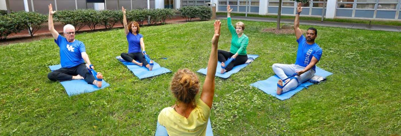 Four yoga students seated outside with instructor