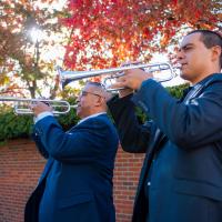 Adiel Nájera and his father play their trumpets together while standing outdoors on the University of Kentucky campus.