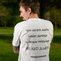 Cameron stands with his back to the camera displaying the phrase on the back of his shirt.