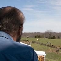 Howard Galbreath, seen from behind, overlooks his farm from above.